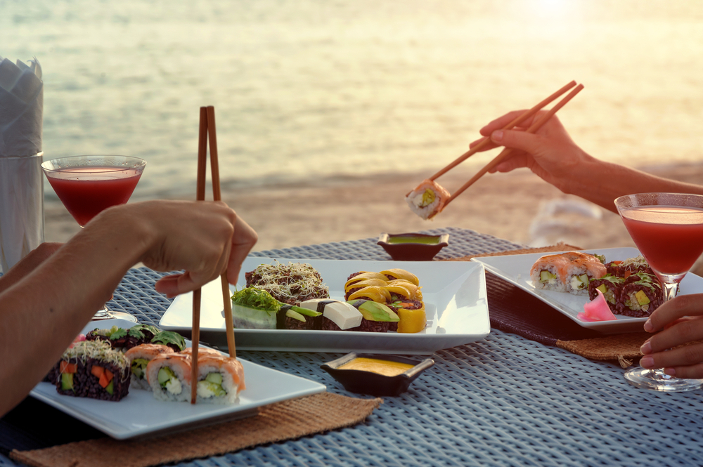 people eating sushi next to the water at a beach restaurant in Fort Myers